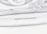 Close-up of a white fabric with decorative gray swirls and black text "www.pok-ta-pokwear.com.mx" along the seam, reminiscent of the intricate design on Classic Sportswear's Gallagher Chiefs Super Rugby Replica Away Jersey 25/26.