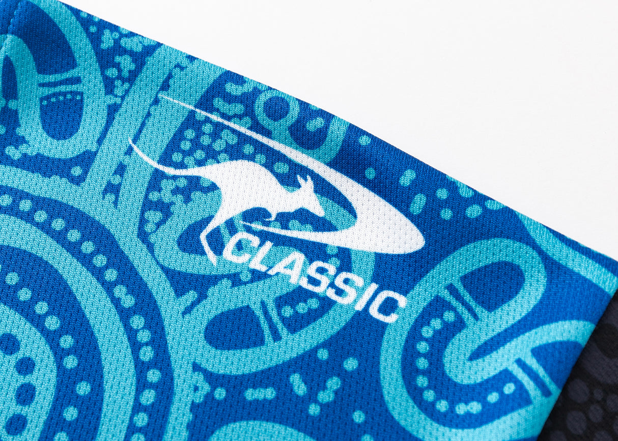 Close-up of a blue and teal patterned fabric with a white kangaroo logo and "CLASSIC," capturing the timeless appeal of the NRL Indigenous All Stars 25/26 Replica Home Jersey by Classic Sportswear.