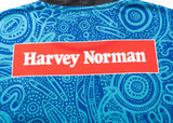 A blue patterned fabric featuring a red rectangle with "Harvey Norman" in white, similar to the NRL Indigenous All Stars 25/26 Replica Home Jersey by Classic Sportswear.