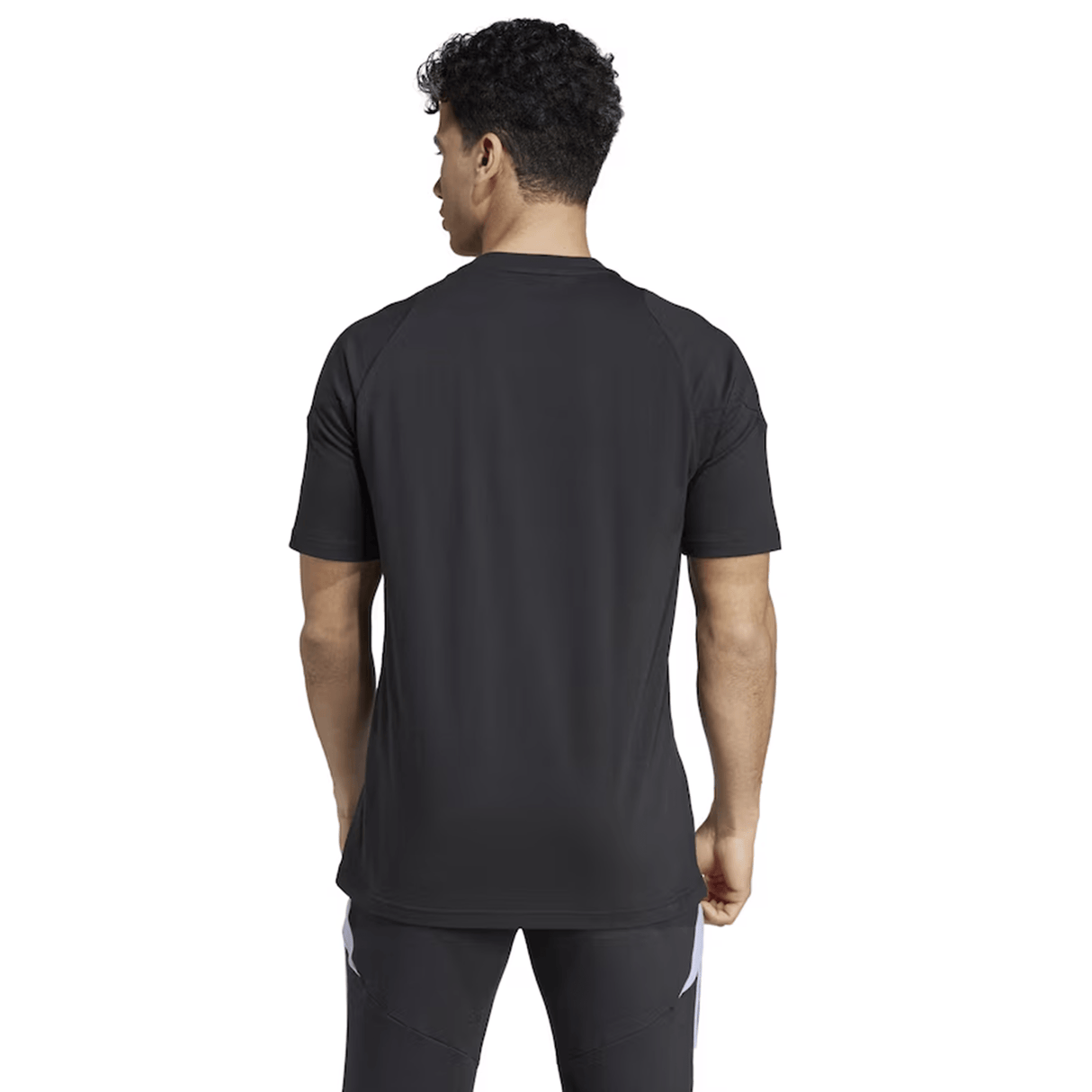 A person with short curly hair is standing with their back turned, wearing a black athletic outfit, similar to the All Blacks 24/25 Performance Cotton T-Shirt by adidas.