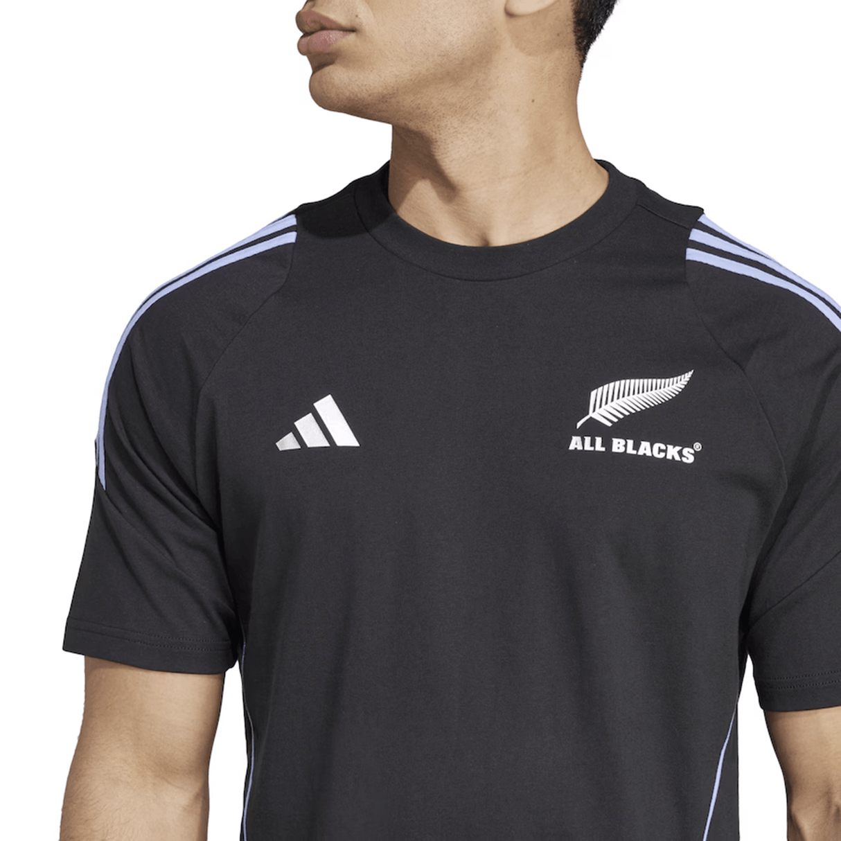 An individual is dressed in the black All Blacks 24/25 Performance Cotton T-Shirt by adidas, showcasing the legendary "All Blacks" logo and distinctive fern emblem, honoring the famous New Zealand rugby team.