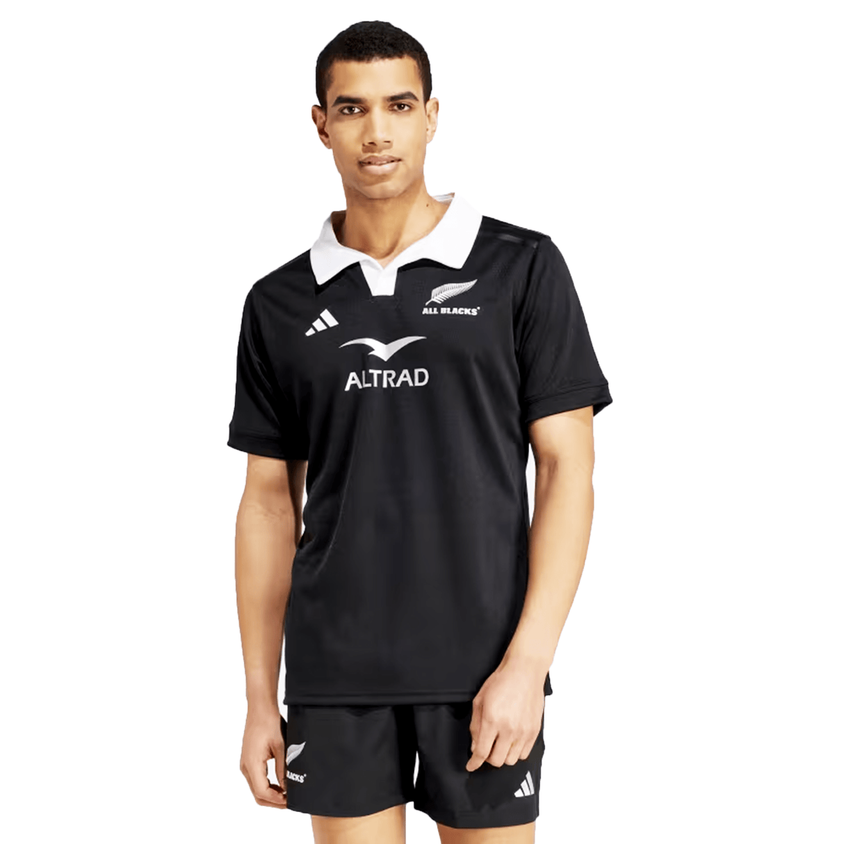 A man wearing the All Blacks 24/25 Home Supporters Jersey by adidas, featuring a white collar and "All Blacks" and "Altrad" logos, stands facing the camera, proudly showcasing the advanced AEROREADY technology.