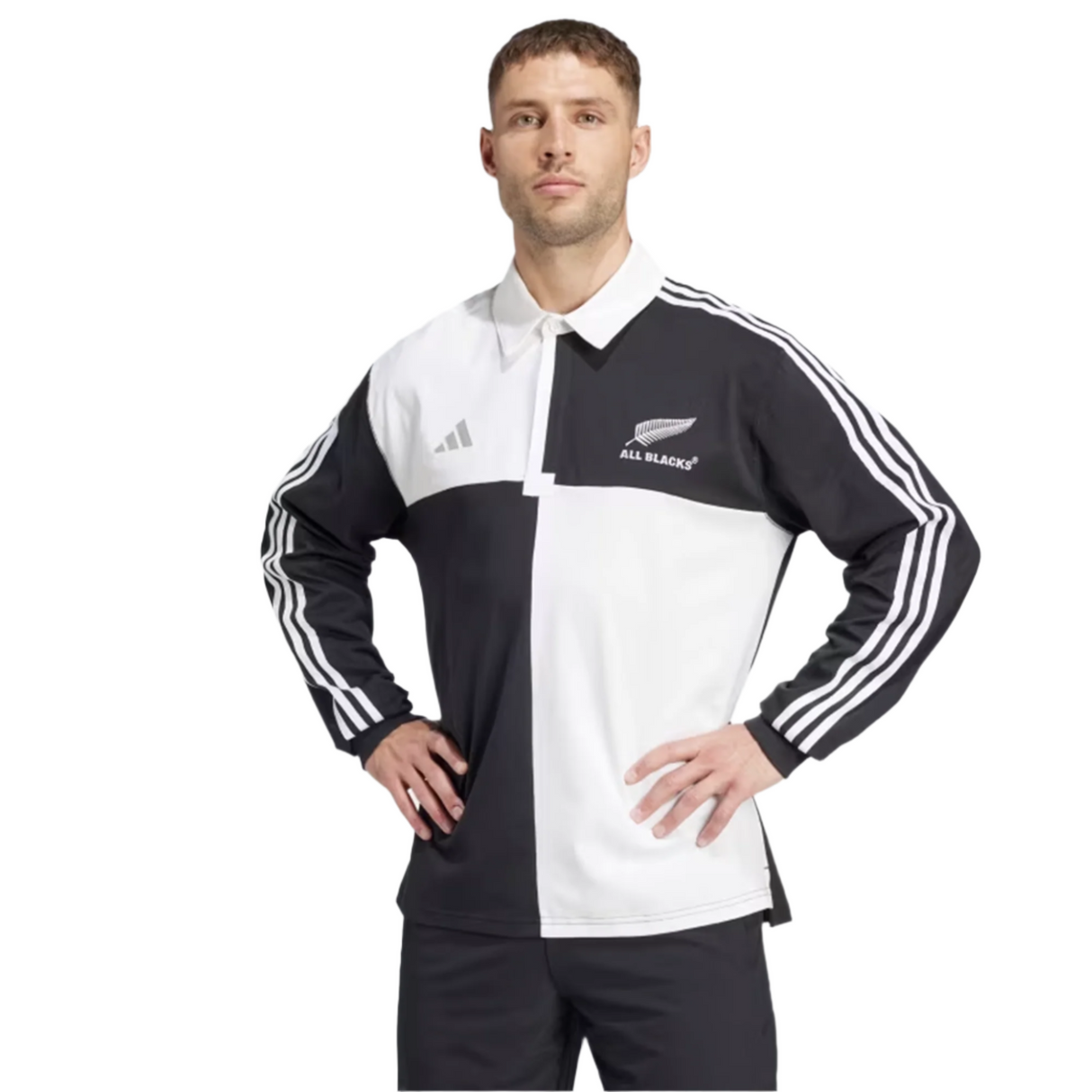 An individual wearing the All Blacks 24/25 Culture Jersey by adidas, featuring black and white stripes and "All Blacks" text, stands with hands on hips against a plain background.