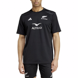 A person is wearing the All Blacks 24/25 Supporters T-Shirt by adidas, a black jersey featuring "Altrad" and "All Blacks" logos, white shoulder stripes, and AEROREADY technology for comfort.