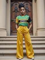 In front of a decorative wooden door, a person stands wearing Admiral's Nations of Rugby Jamaica Supporters Jersey and yellow pants, with arms relaxed at their sides.