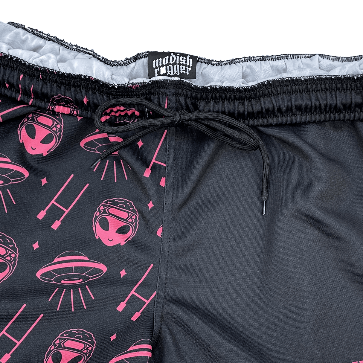 These unisex limited-edition rugby shorts from Modish Rugger, named "We Scrum in Peace," showcase a fun alien and UFO design in pink on black. They feature a sleek black drawstring waist and are labeled "modish jogger.