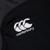 The Canterbury Vapodri Evader Jersey, crafted in black fabric and adorned with the iconic Canterbury logo featuring three stylized overlapping white "C" letters embroidered on it, incorporates advanced VapoDri moisture-wicking technology.