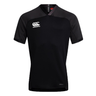 The Canterbury Vapodri Evader Jersey by Canterbury features a black design, short sleeves, a V-neck, and a prominently displayed Canterbury logo on the upper left chest. It is equipped with a moisture-wicking VapoDri finish for added comfort.