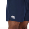 A man is wearing a Canterbury Anchor Tactic Short, a Canterbury navy short with white logos, from his wardrobe.