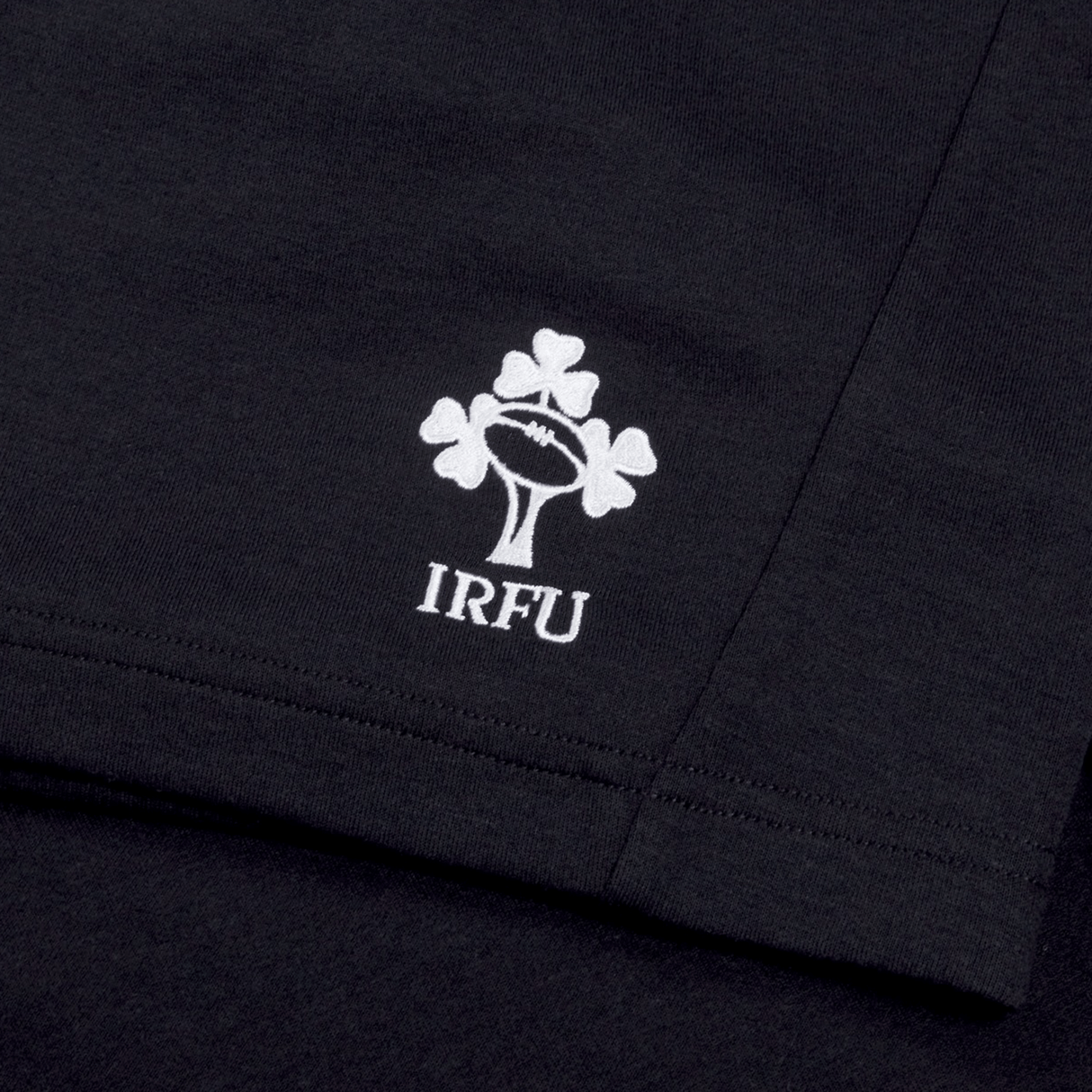 Close-up of the black fabric on the Ireland 24 Fleece Short by Canterbury, showcasing a white logo with a rugby ball and three shamrocks above the letters "IRFU".