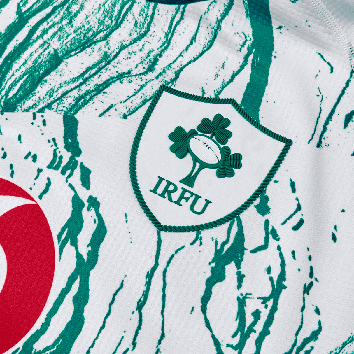 Close-up of the Irish Rugby Football Union (IRFU) logo on a green and white Ireland 24 Alternate Pro Jersey by Canterbury, featuring abstract patterns and crafted from moisture-wicking fabric for elite performance.