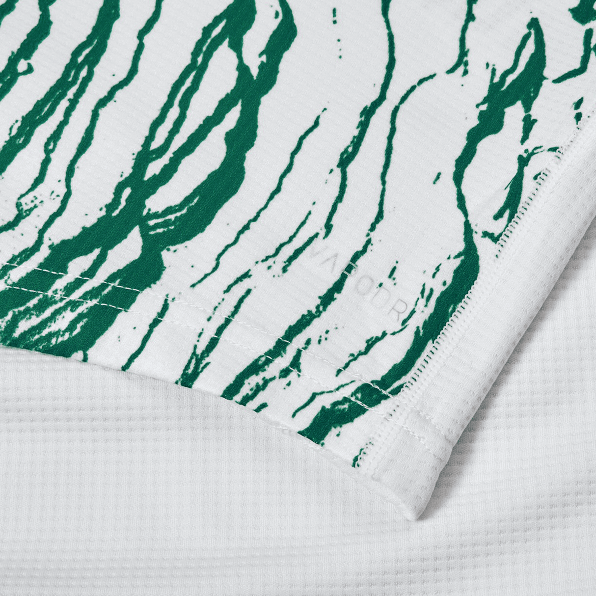 A close-up image of a white fabric with green, wavy lines reminiscent of the Ireland 24 Alternate Pro Jersey by Canterbury. The fabric layers overlap slightly, showcasing elite performance stitching details and moisture-wicking properties indicative of Canterbury's high-quality craftsmanship.