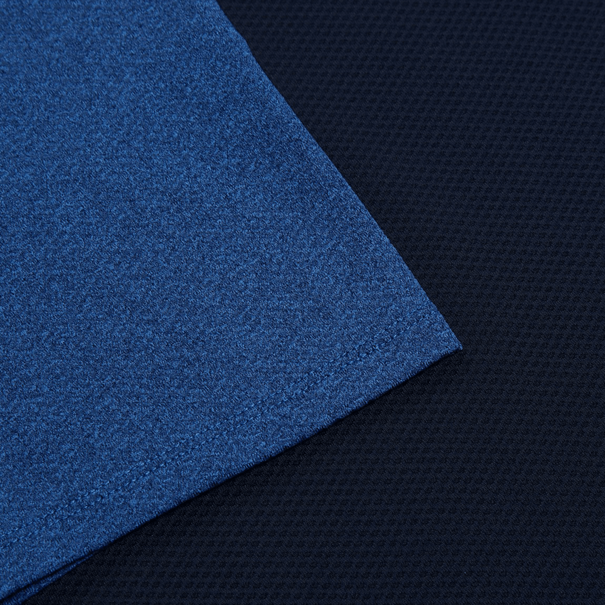 Close-up of a folded blue fabric corner on a textured dark surface, highlighting the lightweight Women's Canterbury Elite Training Tee with Vapodri technology.