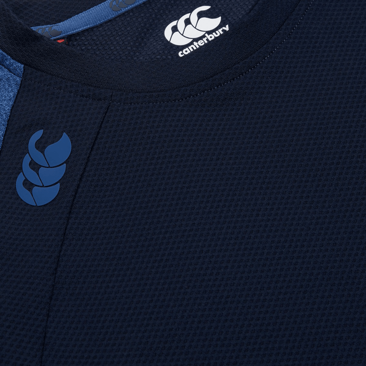 Close-up of the top section of a navy Canterbury Women's Canterbury Elite Training Tee, featuring its brand logo. This tee is crafted with lightweight fabric and enhanced by Vapodri technology, ensuring ultimate comfort.