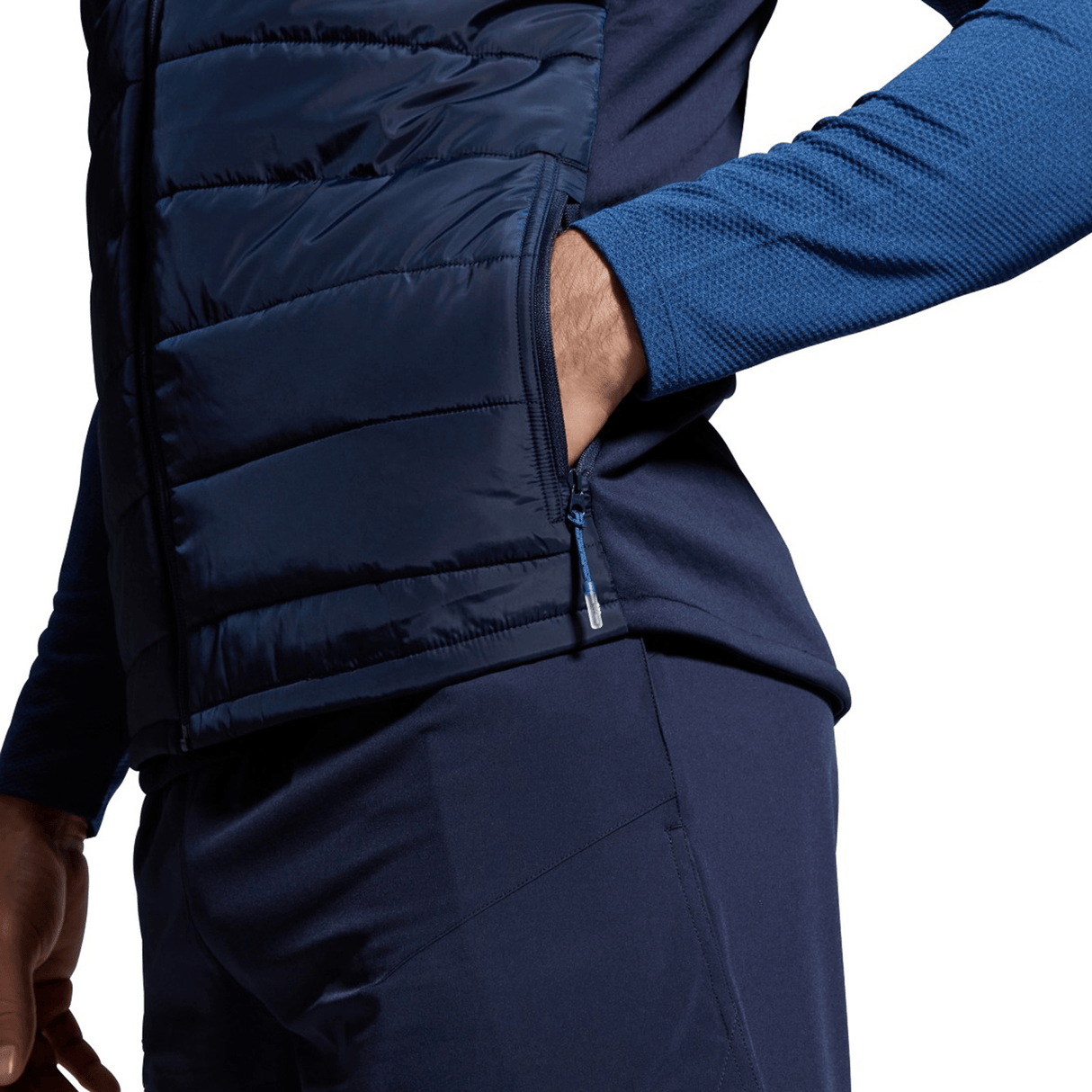 Close-up of a man wearing a navy blue Canterbury Elite Microlite Gilet over a blue long-sleeve shirt, focusing on the side zipper detail.