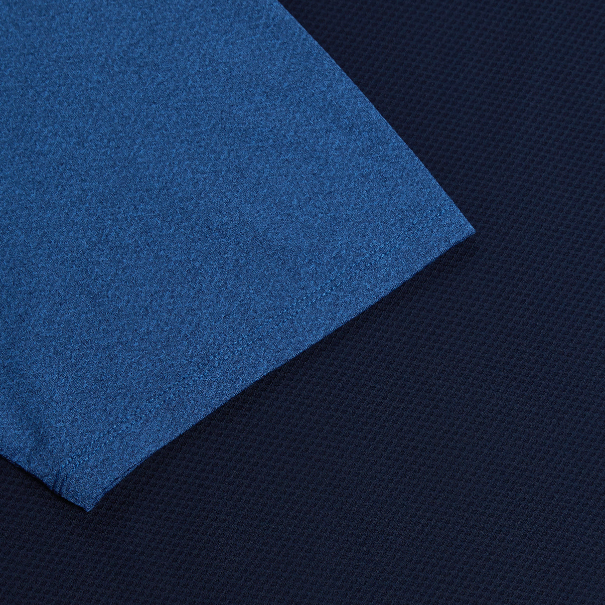 An Canterbury Elite Training Tee in Canterbury blue placed on a black surface.