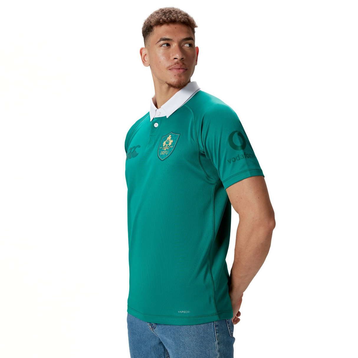 A man wearing the Ireland 150th Anniversary Pro Home Jersey by Canterbury, featuring a white collar and logo, stands with hands behind his back, looking to the side. This jersey celebrates its heritage with Vapodri Technology for enhanced performance.