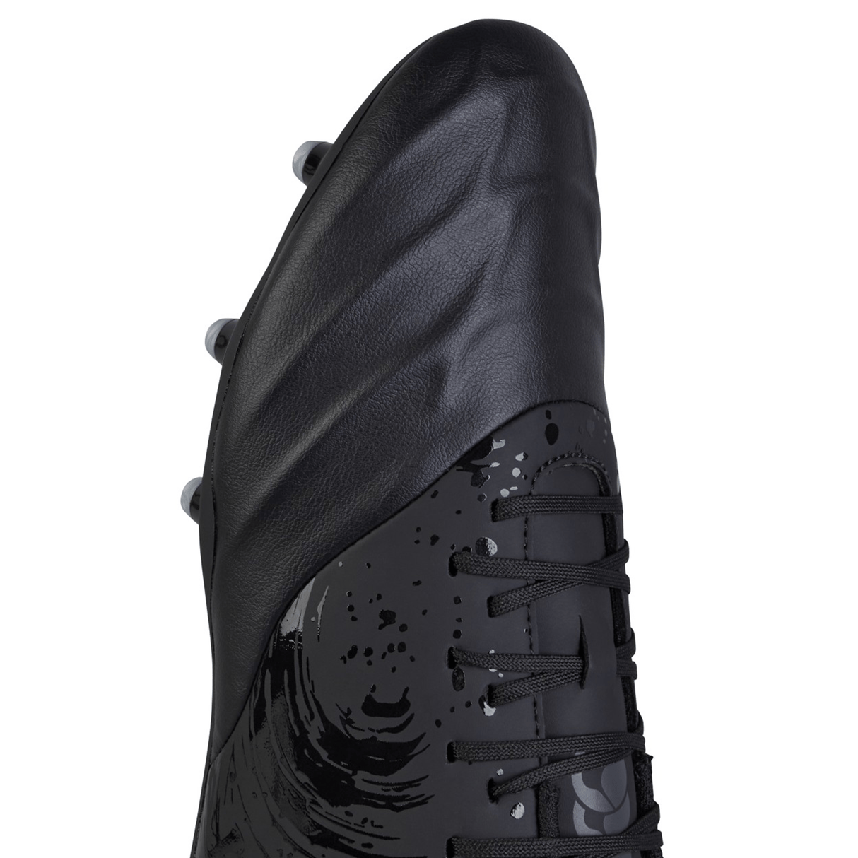 Close-up image of the Canterbury Phoenix Genesis Team FG - Black/Silver Metallic firm ground boot, showcasing a patterned design, lacing, and metal studs on the synthetic leather forefoot.