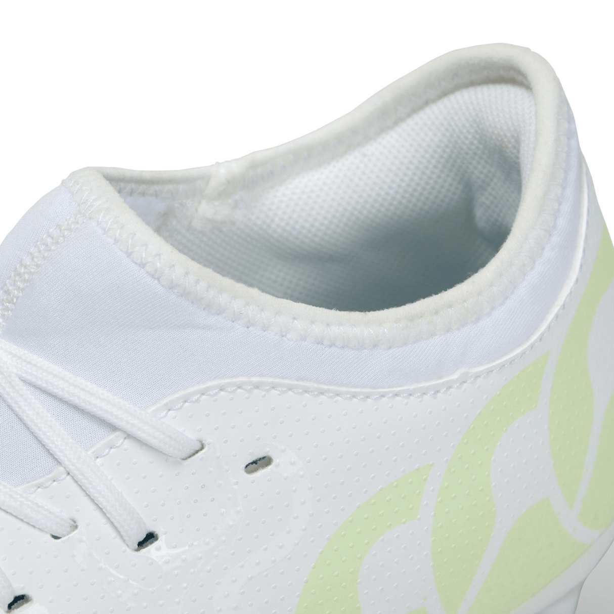 Close-up of a white and neon green Canterbury Speed Infinite Team FG rugby boot showing details of the lacing, ventilation holes, and lightweight design pattern.