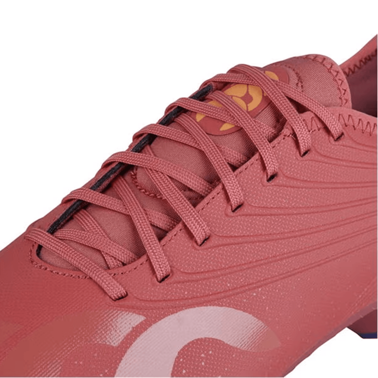 Close-up of a pink Canterbury Stampede Groundbreak Team SG soccer cleat with intricate stitching and laces, featuring an amber yellow circular logo near the tongue. This soft ground boot boasts an EVA footbed for added comfort and support on the field.