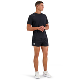 A person in black Canterbury Classics Rugged Drill Shorts with an elasticated waist and white sneakers stands with hands clasped.