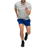 A person running toward the camera in a gray t-shirt, Canterbury Classics Rugged Drill blue shorts, and black sneakers against a white background.