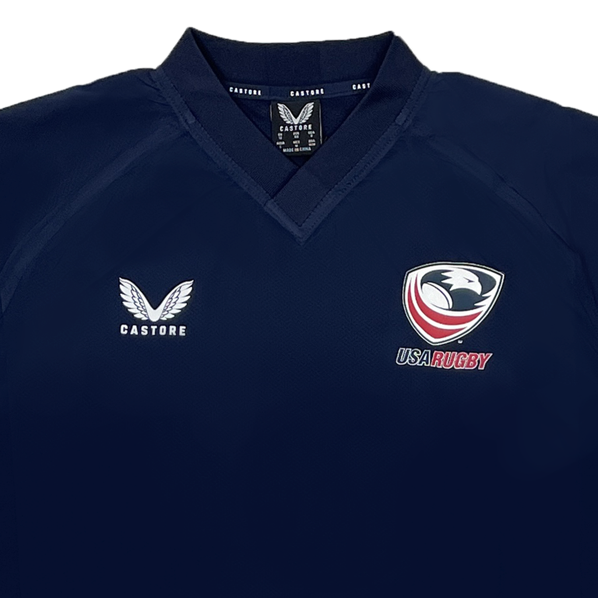 The Women's USA Rugby Weatherproof Top by Castore is a navy blue jersey with the Castore logo on the left and the USA Rugby emblem on the right, designed for optimal performance.