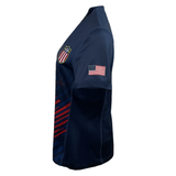 Side view of the USA Rugby Women's 2024 Olympic 7's Jersey by Castore, showcasing a dark blue color with an American flag on the sleeve and a "USA" shield patch on the chest. Created by Castore, this jersey encapsulates both style and patriotism.