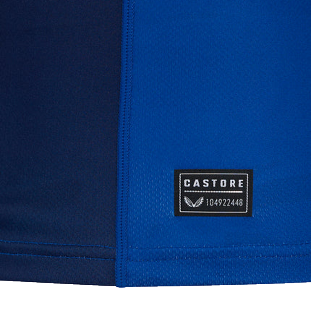 Close-up of a blue fabric with a black rectangular label featuring "CASTORE" and the number "104922448" in white text, showcasing its athletic fit. An ideal choice for those looking for a stylish Leinster 24/25 Replica Home Jersey by Castore.