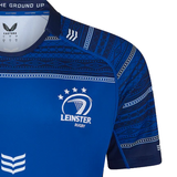 The Leinster 24/25 Replica Home Jersey by Castore, in a striking blue color, boasts an Irish Harp Graphic along with a prominent white logo and star design. Its patterned details on the shoulders and sleeves enhance the athletic fit, highlighting its sleek style.