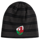 The Wales Shield Beanie by EMB Canterbury is a black and gray striped beanie showcasing a fierce red dragon emblem on a classic white and green shield.