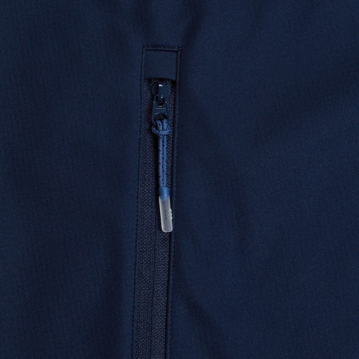 Close-up of a dark blue zipper partially closed on a garment with a navy fabric background, featuring weatherproofing elements of the Canterbury Elite Windstopper Jacket.