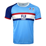 Light blue jersey with round neck and short sleeves. Right shoulder and sleeve in dark blue trimmed in red. Left sleeve in light blue trimmed in red. Fiji partial flags on upper left chest with Fiji Rugby in the center of red and dark blue horizontal lines.