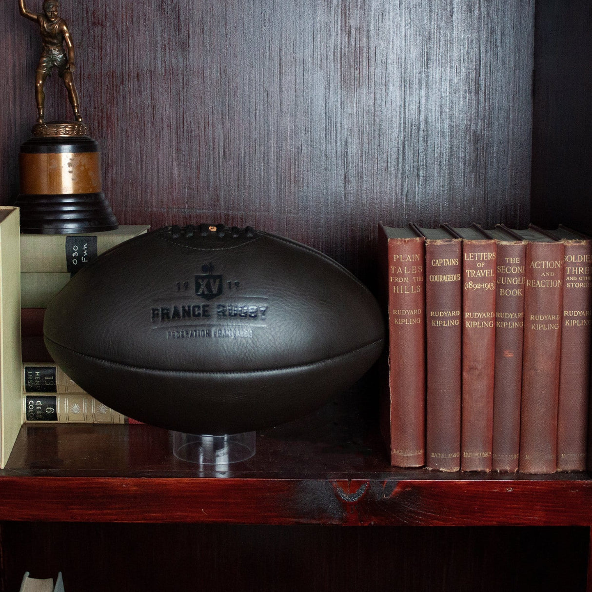 A France Vintage Leather Ball by Gilbert on a shelf next to books.