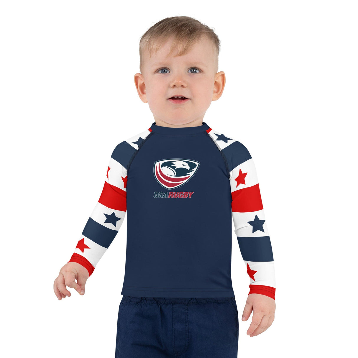 Little boy wearing a Long sleeve rash guard with a red, white and blue stars and stripes design on the sleeves, a navy body and a USA Rugby logo center front.