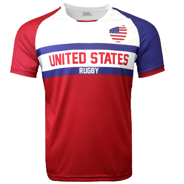 Round neck short sleeve jersey with white chest and upper left American flag in corner. Red right shoulder and sleeve and blue left shoulder and sleeve trimmed in red. Two horizontal blue stripes run across the chest. United States centered in red on the white jersey with Rugby in white on the blue stripe. The lower torso is red.