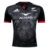 This Māori All Blacks Home Supporters Jersey by adidas comes in black and showcases an intricate Māori-inspired design. Made from recycled polyester, it features moisture-wicking fabric along with the Adidas and Altrad logos, and prominently displays the text "Māori All Blacks.