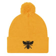 A Rugby Hive Gold Pom-Pom Beanie with a black bee on it.