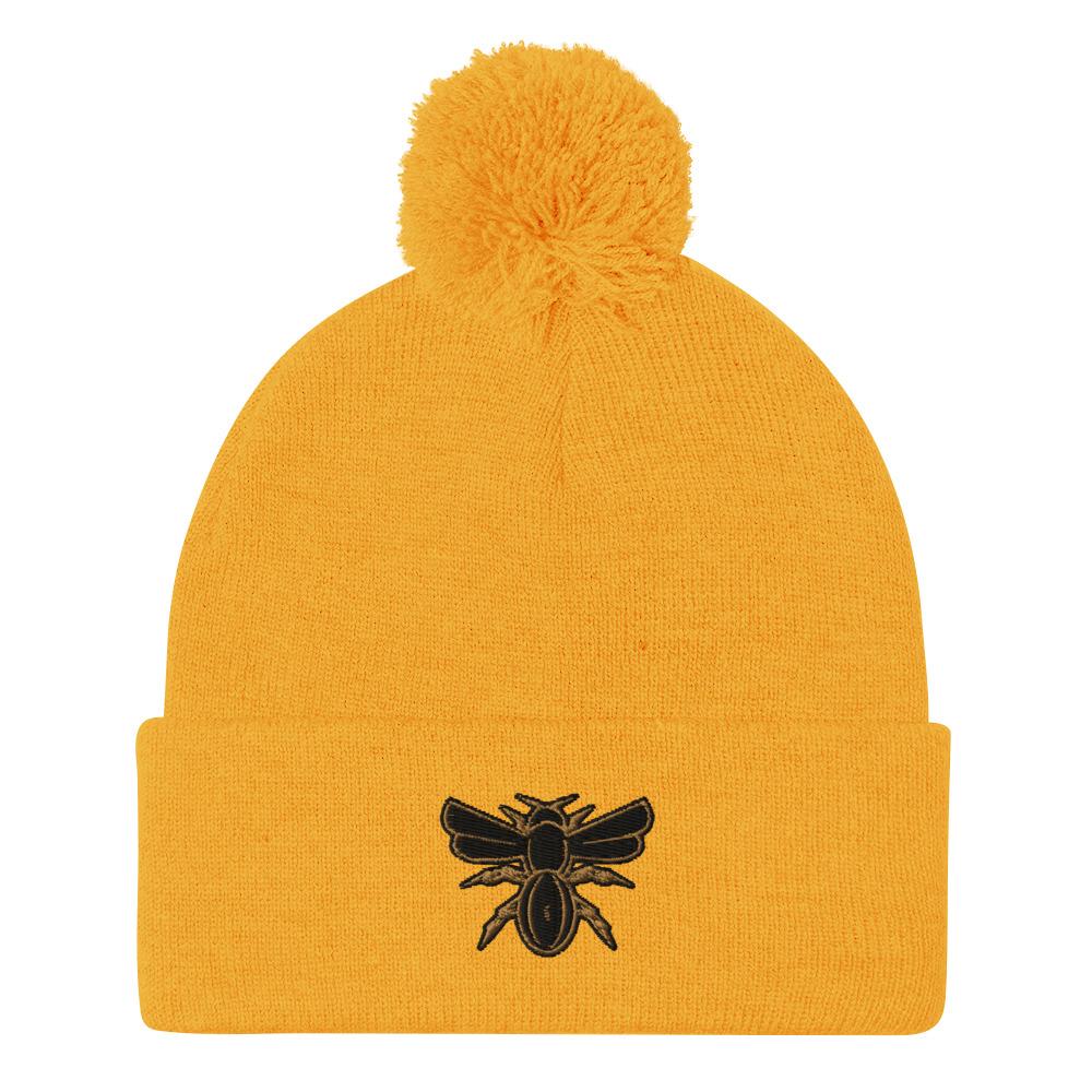 A Rugby Hive Gold Pom-Pom Beanie with a black bee on it.