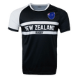 Round neck short sleeve jersey. White right shoulder trimmed in black. Chest and right shoulder in black. Two white center stripes with New Zealand in the center and Rugby below. The New Zealand flag sits on the upper left chest.